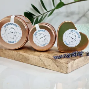 baume fouetté en trois formats différents (grand pot rond , petit pot rond et petit cœur), posé sur un support en bois de face avec l'étiquette Savonnier Soapy