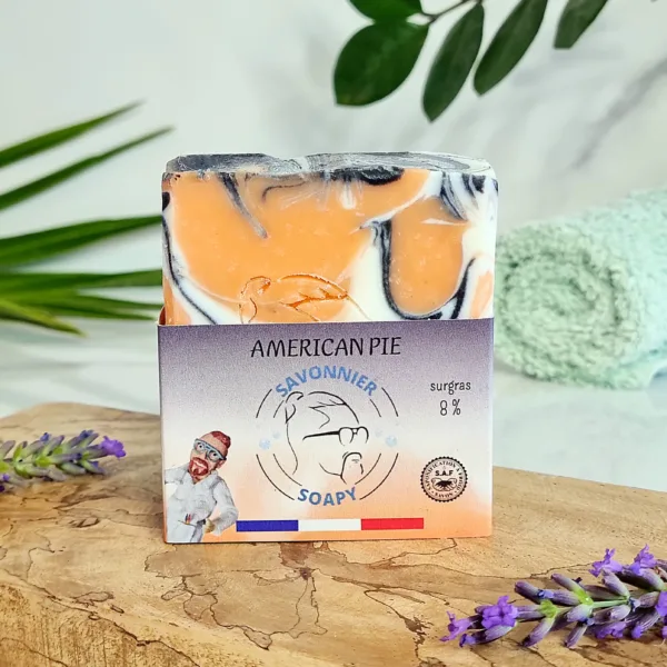Savon pour peaux grasses de face, marbré orange et blanc, posé sur support bois. surgras à 8%